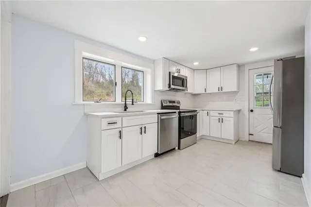 a kitchen with white cabinets stainless steel appliances and a window