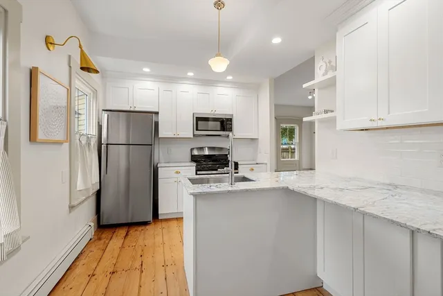 a kitchen with kitchen island a refrigerator a stove a sink and a oven with wooden floor