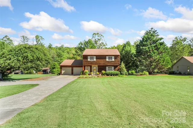 a view of a house with a big yard and large trees