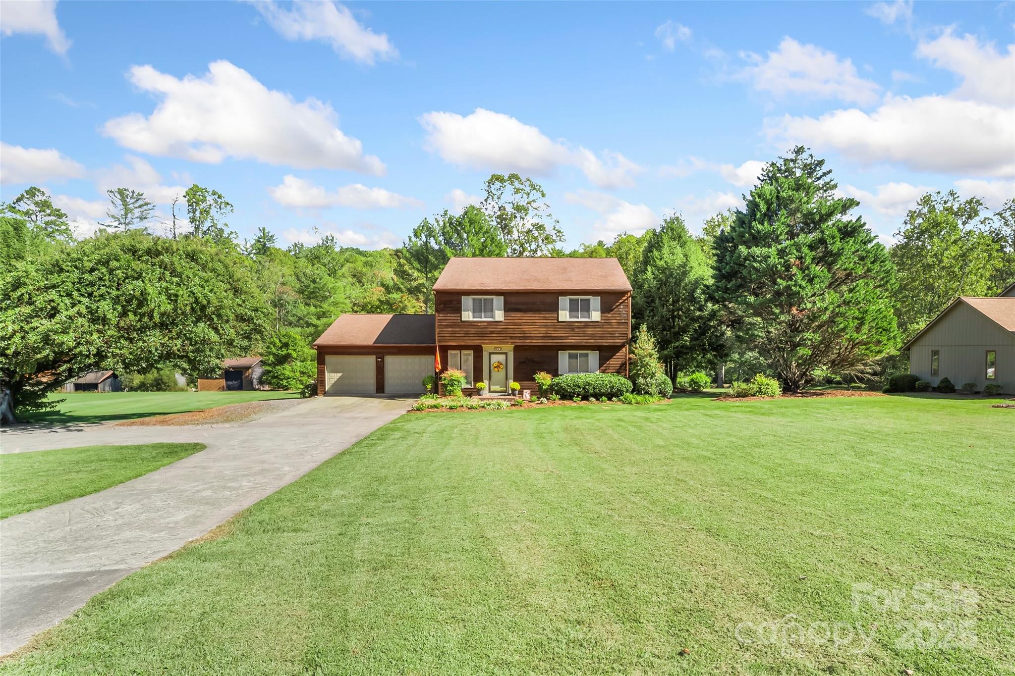 a view of a house with a big yard and large trees