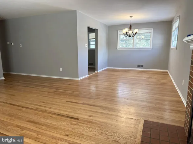 an empty room with wooden floor and chandelier