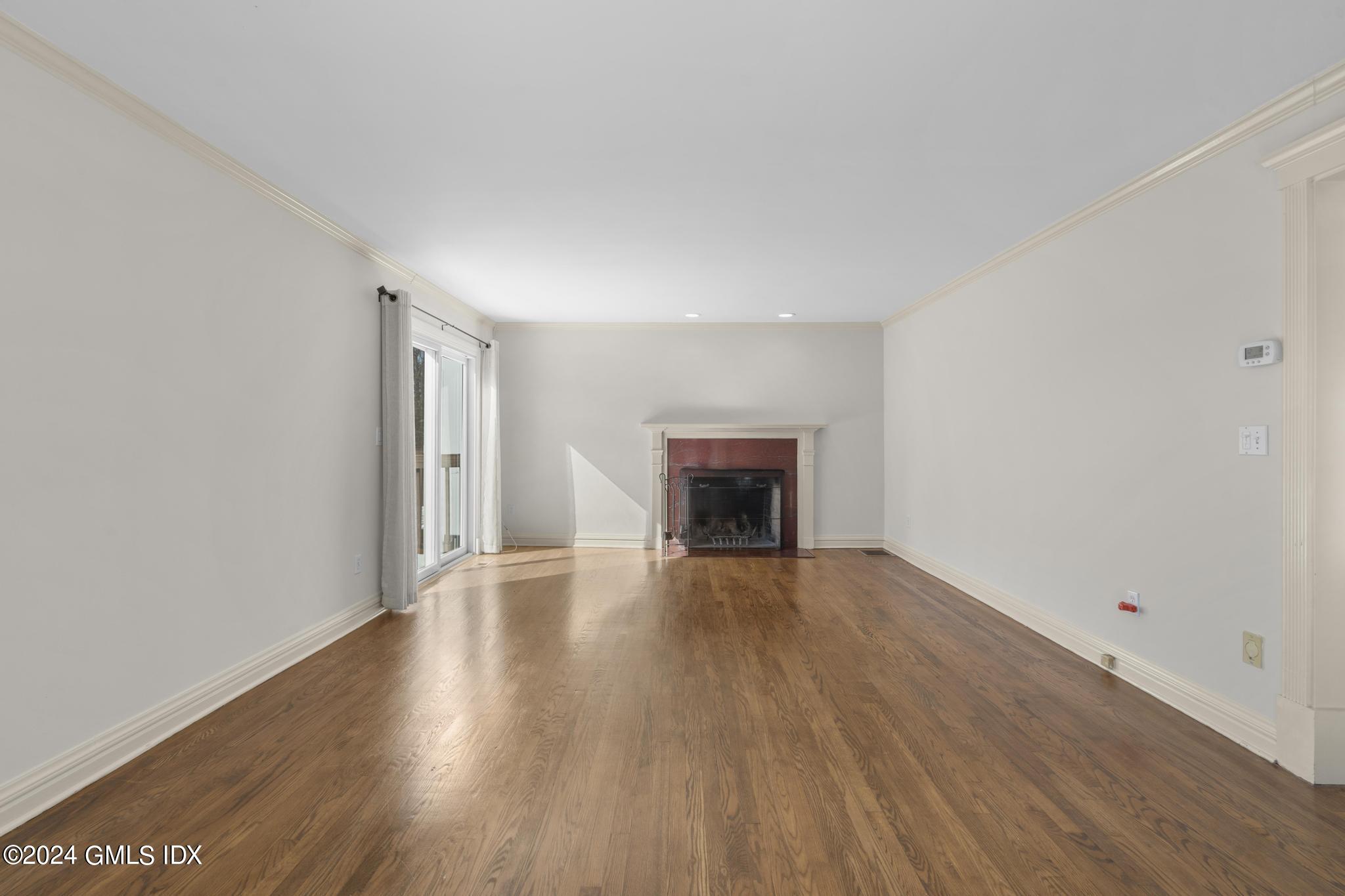 172 Field Point Road, Unit 1 Greenwich, CT 06830 - Photo 6 of 36 an empty room with wooden floor and fireplace