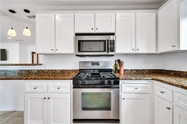 a kitchen with granite countertop white cabinets and stainless steel appliances