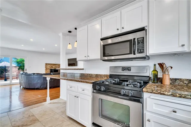 a kitchen with granite countertop a stove top oven microwave and cabinets