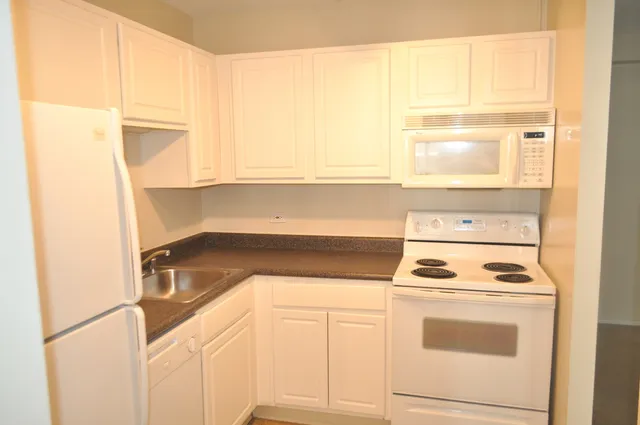 a kitchen with white cabinets and white appliances
