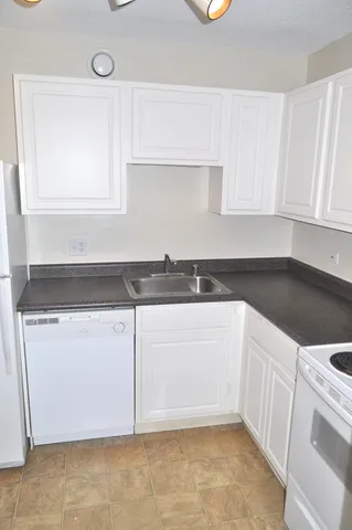 a kitchen with granite countertop white cabinets and white appliances