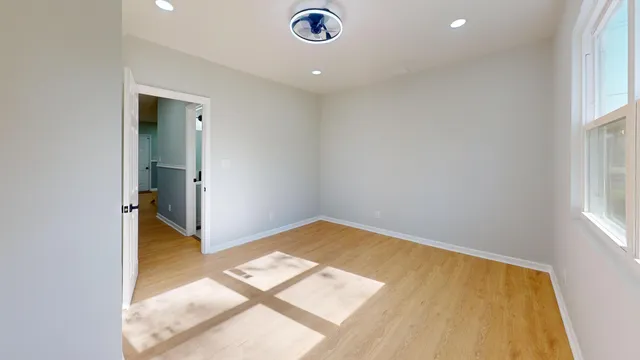 an empty room with wooden floor and windows