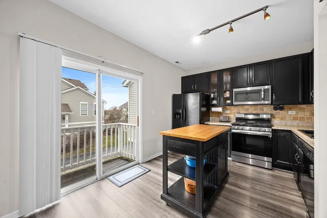 a kitchen with stainless steel appliances granite countertop a stove top oven a sink dishwasher a dining table and chairs with wooden floor