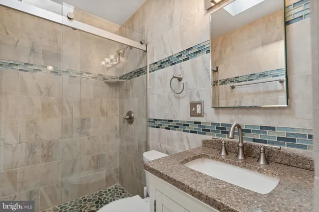 a bathroom with a granite countertop sink a mirror and shower