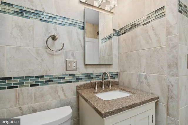 a bathroom with a granite countertop sink a toilet and a mirror