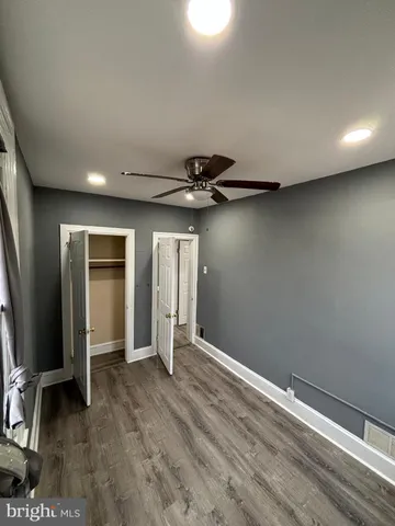 an empty room with wooden floor and a ceiling fan