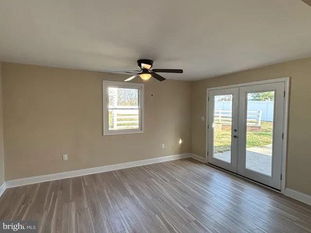 a view of an empty room with a window and wooden floor