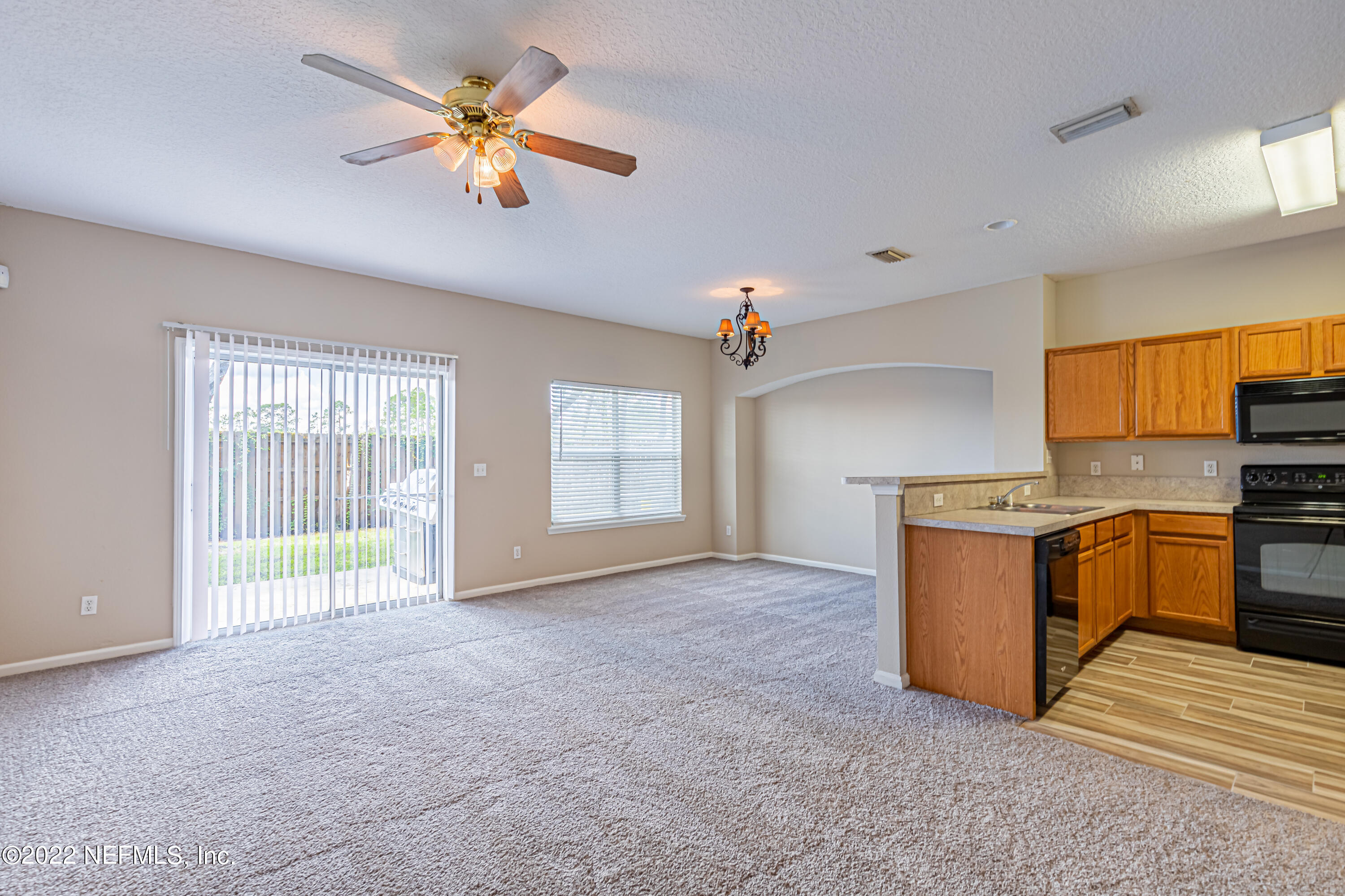 5260 Collins Road, Unit 607 Jacksonville, FL 32244 - Photo 7 of 41 a view of a kitchen with a stove cabinets a ceiling fan and wooden floor