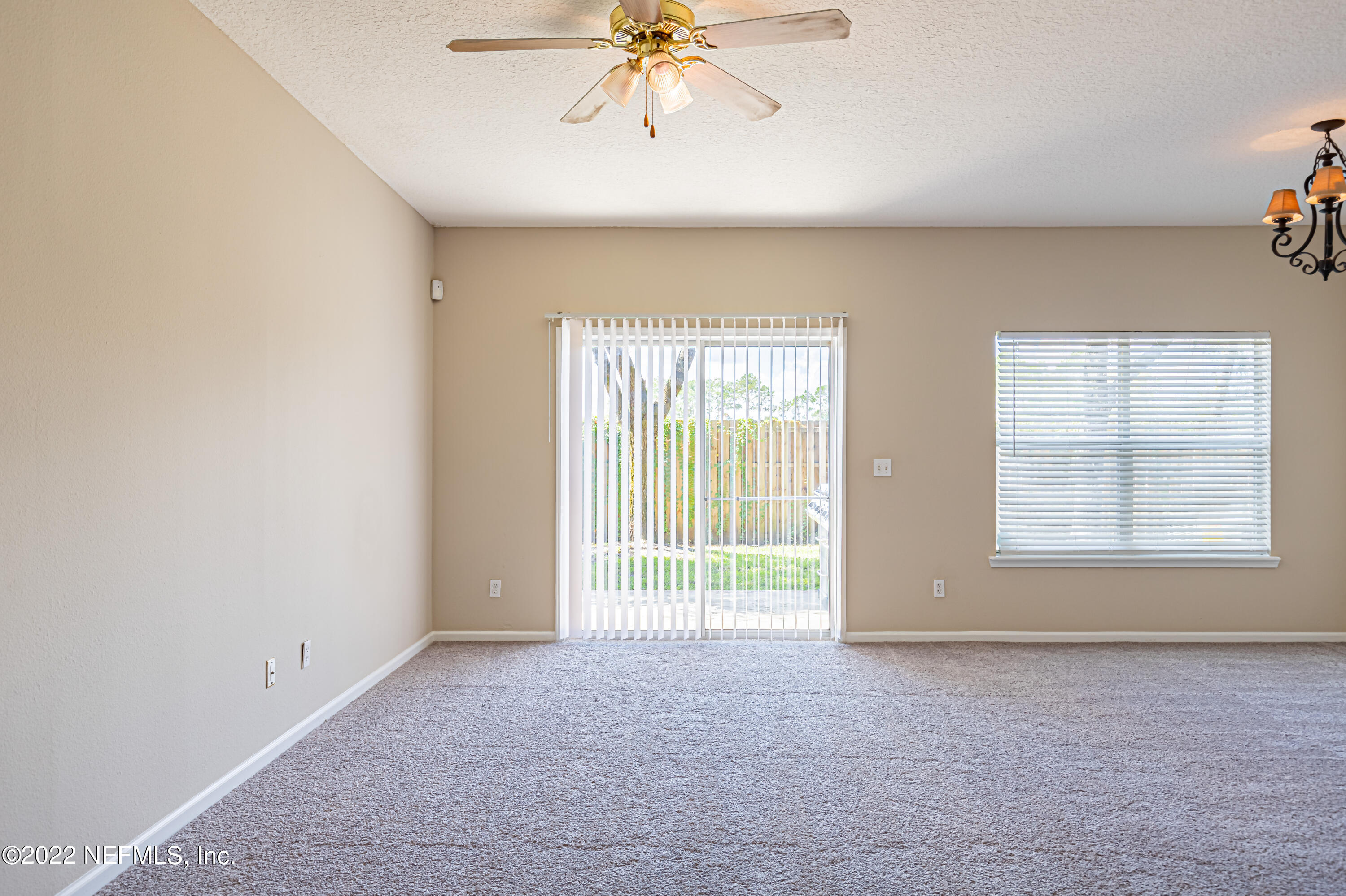 5260 Collins Road, Unit 607 Jacksonville, FL 32244 - Photo 10 of 41 an empty room with chandelier fan and windows