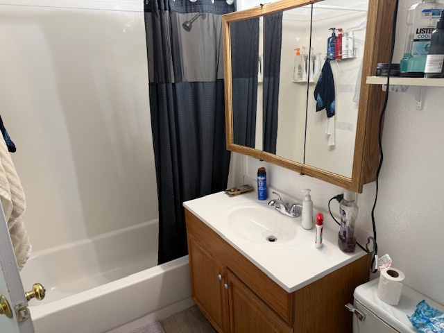 72 880 North, Unit 2 Provo, UT 84604 - Photo 7 of 9 Bathroom featuring a white bathtub with a shower fixture, a wood-finish vanity with an integrated sink, a white countertop, and a mirrored medicine cabinet