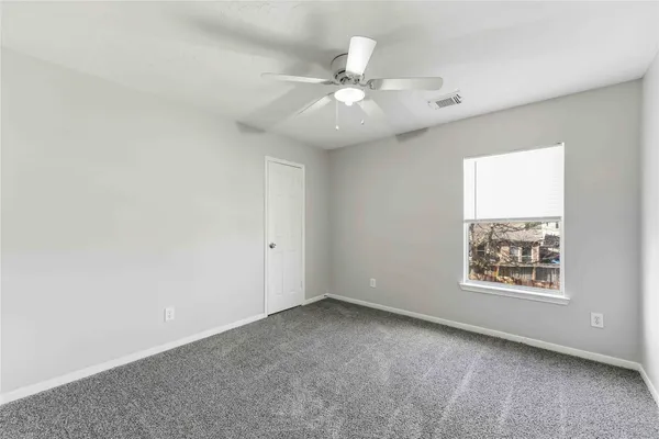 an empty room with windows and fan