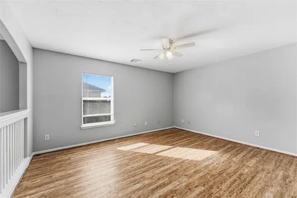 a view of empty room with wooden floor and fan