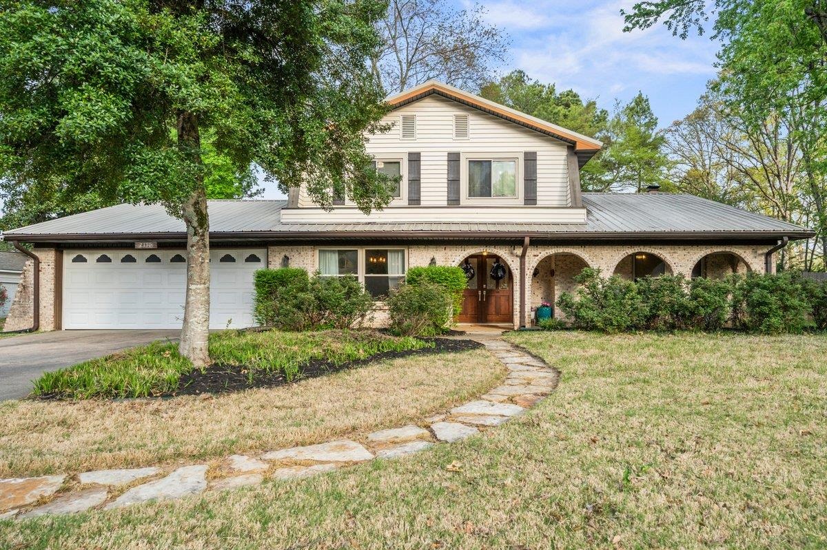 View of front of property featuring a garage, driveway, a front yard, a porch, and brick siding