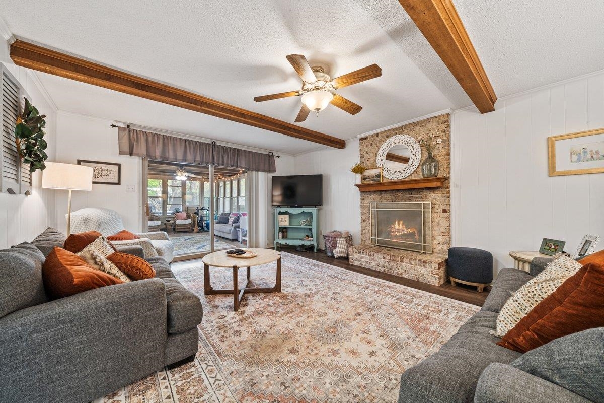 2135 Brierbrook Road Germantown, TN 38138 - Photo 13 of 25 Living room featuring a ceiling fan, beam ceiling, a textured ceiling, a fireplace, and wood finished floors