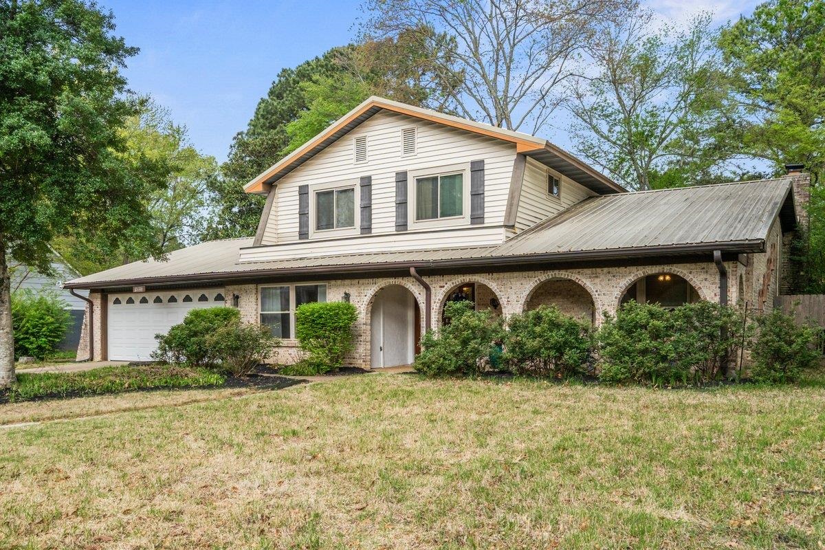 View of front of home featuring a front yard, an attached garage, and brick siding