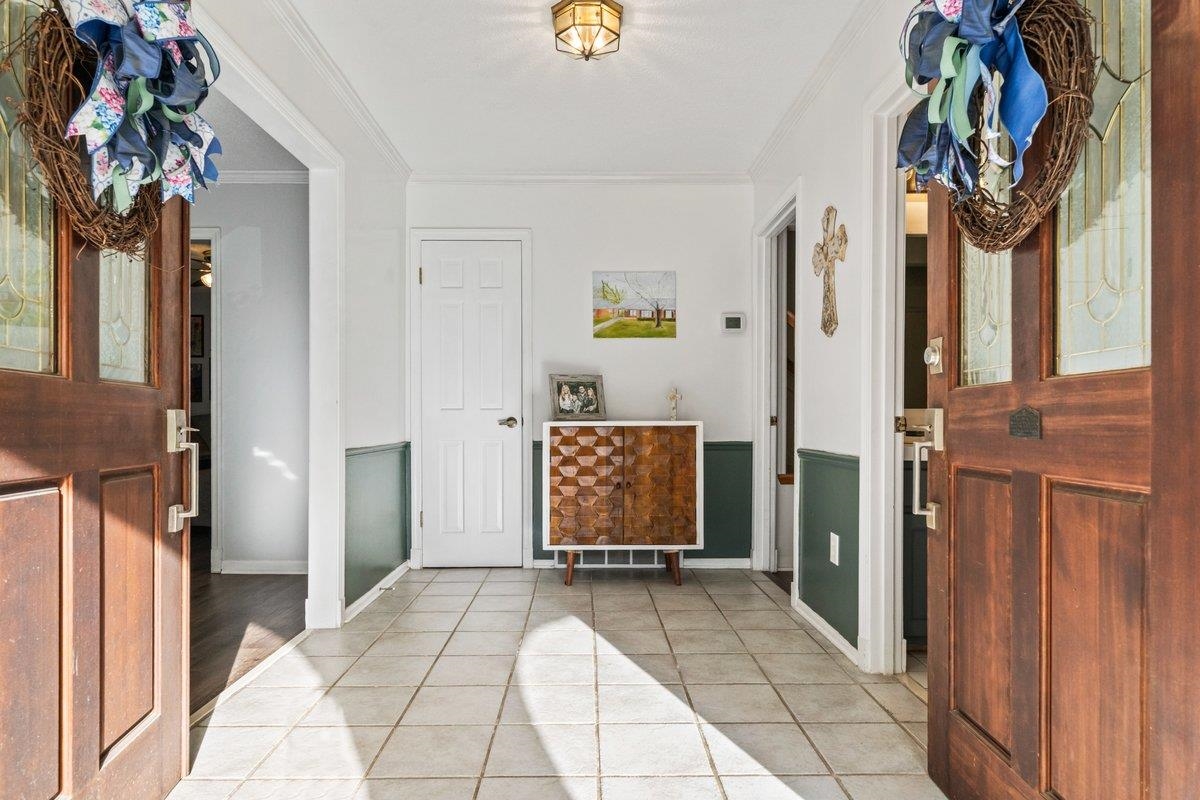 Entryway with light tile patterned floors and crown molding