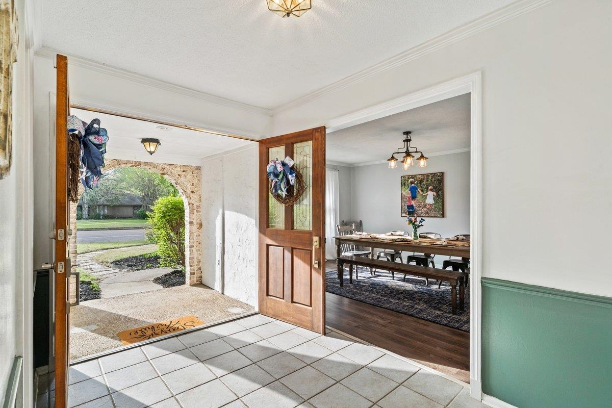 Tiled entryway with crown molding and hanging lights