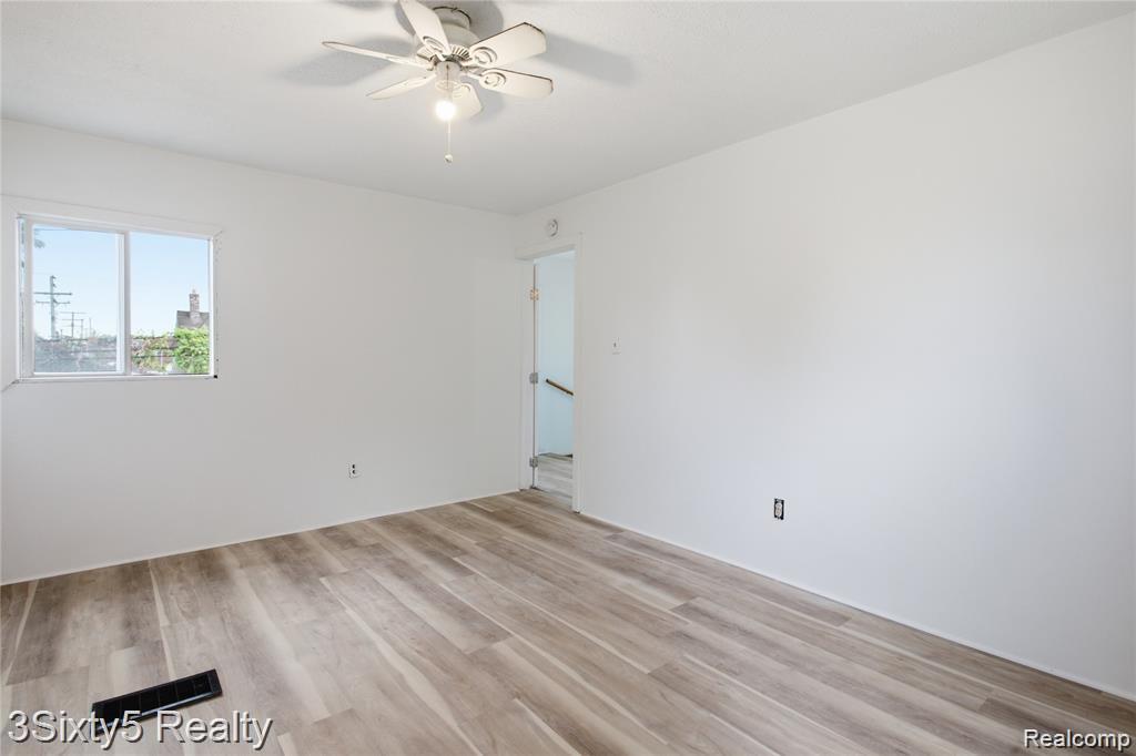147 Charles Street River Rouge, MI 48218 - Photo 12 of 24 Wood-finish flooring, white walls, ceiling fan with light fixture, and a window providing natural light