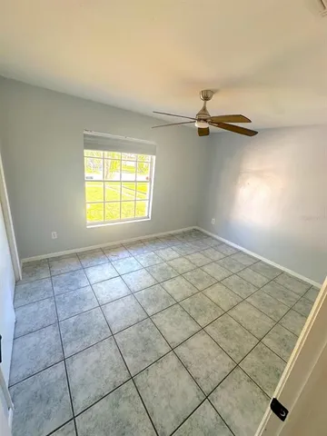 an empty room with windows and ceiling fan