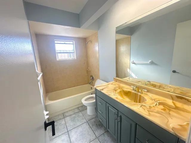 a bathroom with a granite countertop sink a toilet a mirror and bathtub
