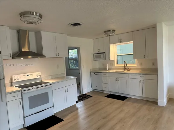 a kitchen with granite countertop a sink cabinets and stainless steel appliances