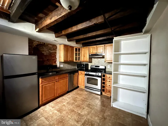 a kitchen with stainless steel appliances granite countertop a refrigerator a stove a sink and a microwave