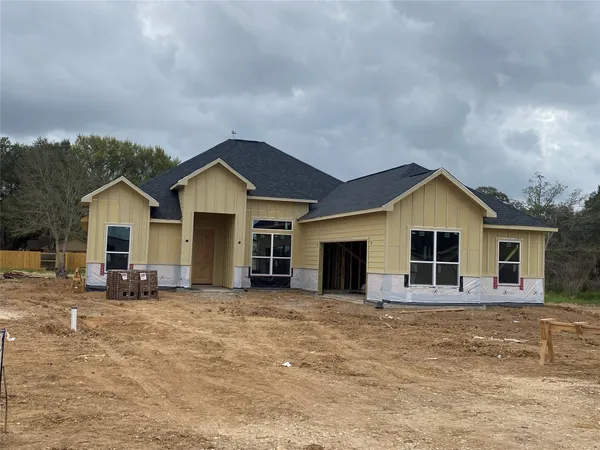a front view of house with yard and trees in the background