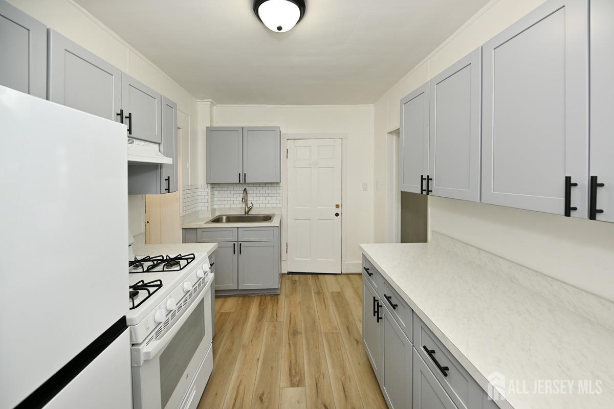 a kitchen with a sink a stove a refrigerator and white cabinets