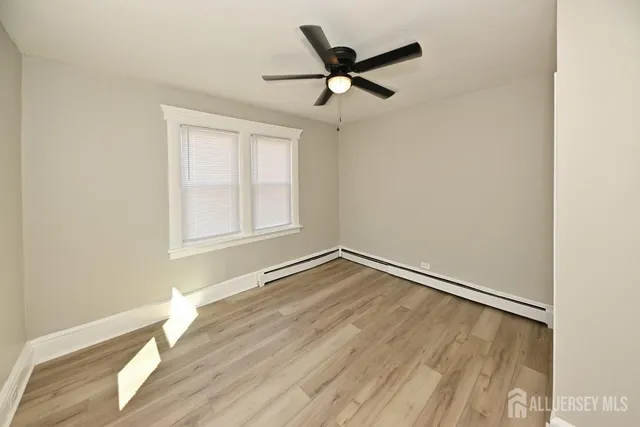 an empty room with wooden floor fan and windows
