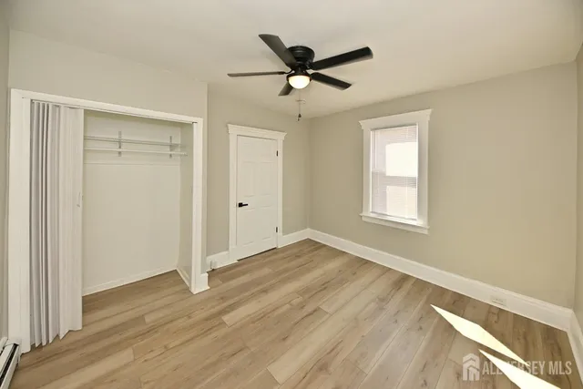 a view of empty room with wooden floor and fan