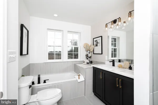 a bathroom with a double vanity sink bathtub mirror and toilet