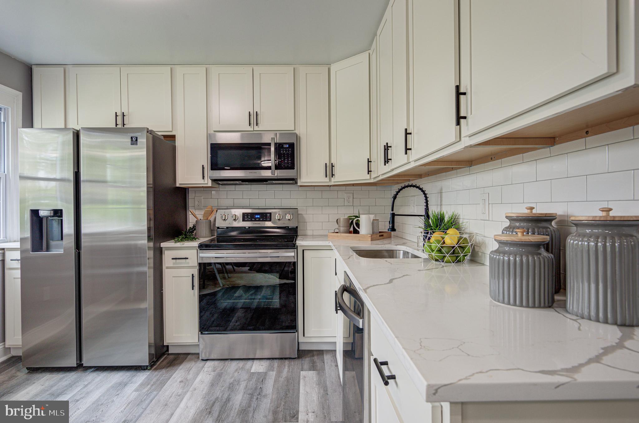 1852 Colmar Road Baltimore, MD 21207 - Photo 6 of 28 a kitchen with a refrigerator a stove and a sink with wooden floor