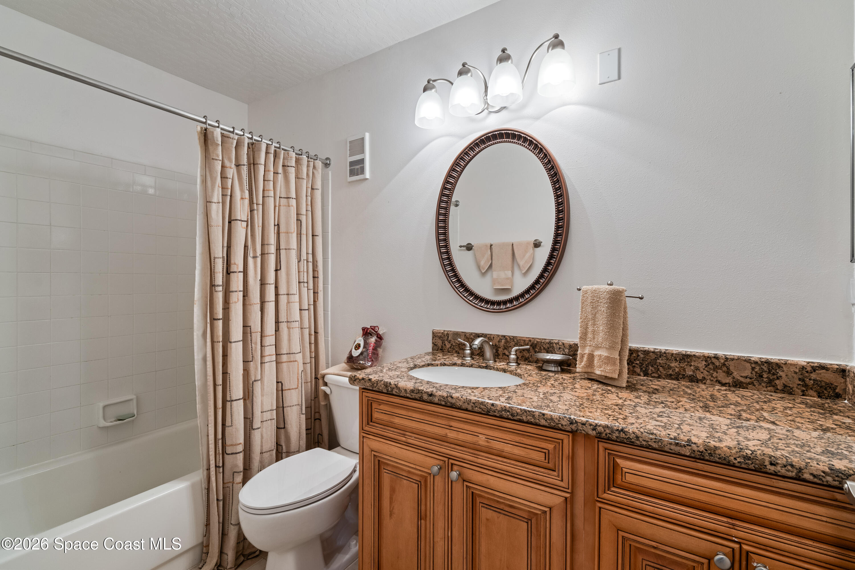 7667 North Wickham Road, Unit 208 Melbourne, FL 32940 - Photo 4 of 33 a bathroom with a granite countertop toilet a sink and a mirror