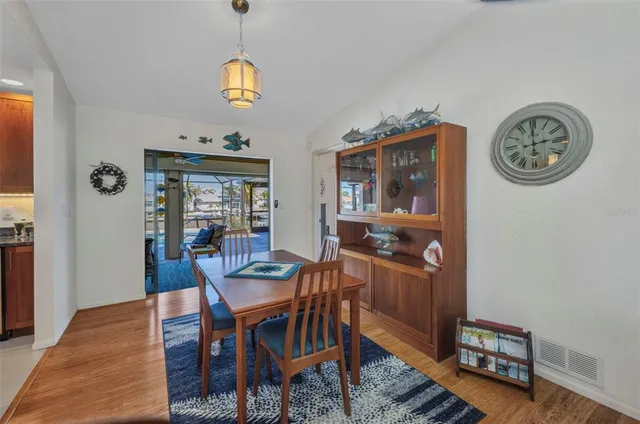 a dining room with wooden floor a chandelier a wooden table and chairs