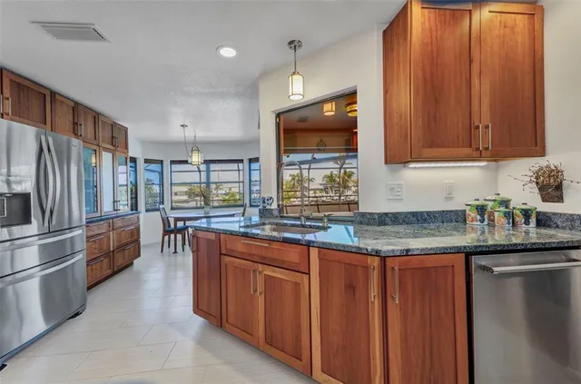 a kitchen with granite countertop a sink stainless steel appliances and cabinets