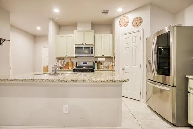 a kitchen with stainless steel appliances granite countertop a refrigerator a stove and a sink
