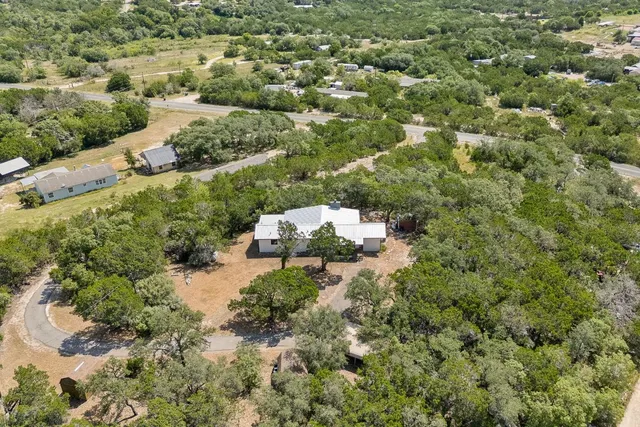 an aerial view of residential house with outdoor space and trees all around
