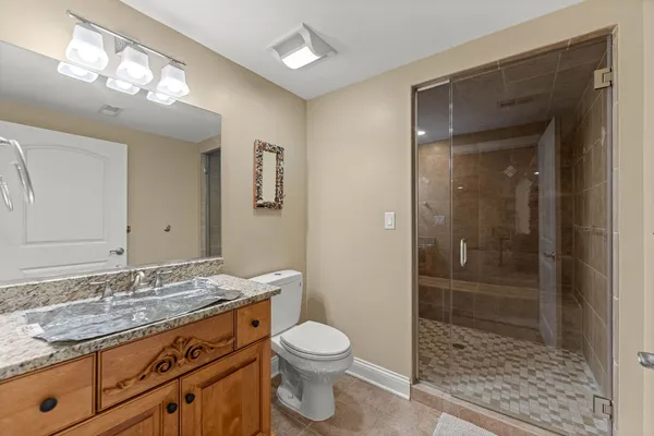 a bathroom with a granite countertop double vanity sink a mirror and shower