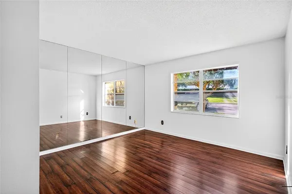 a view of an empty room with window and wooden floor