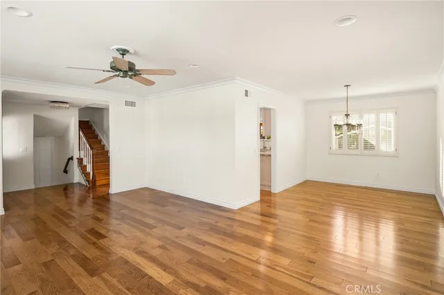 a view of empty room with wooden floor and ceiling fan
