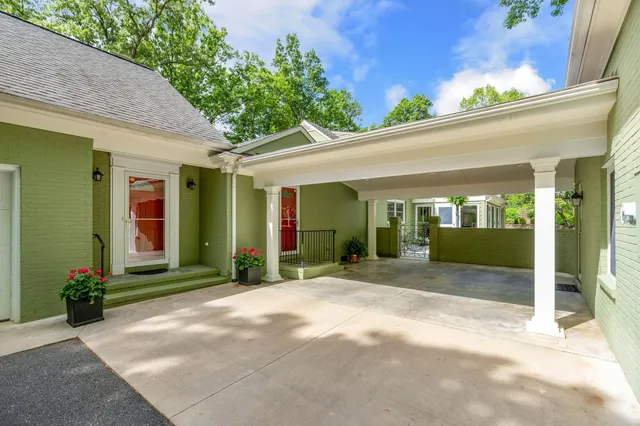 a view of a house with potted plants and a large tree