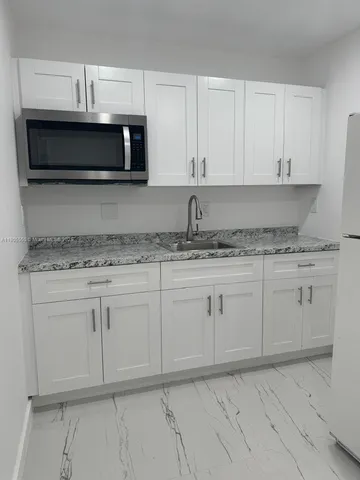 a kitchen with granite countertop white cabinets and stainless steel appliances