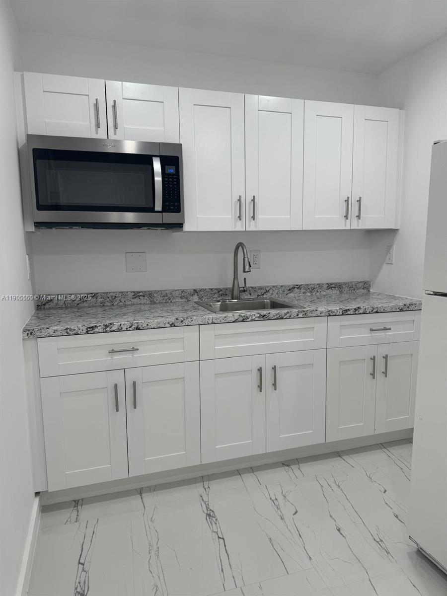 29621 Southwest 165th Court Homestead, FL 33033 - Photo 3 of 7 a kitchen with granite countertop white cabinets and stainless steel appliances