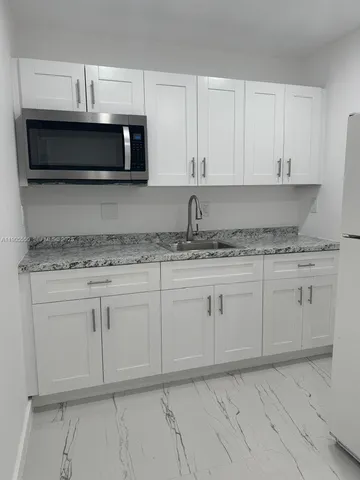 a kitchen with granite countertop white cabinets and stainless steel appliances