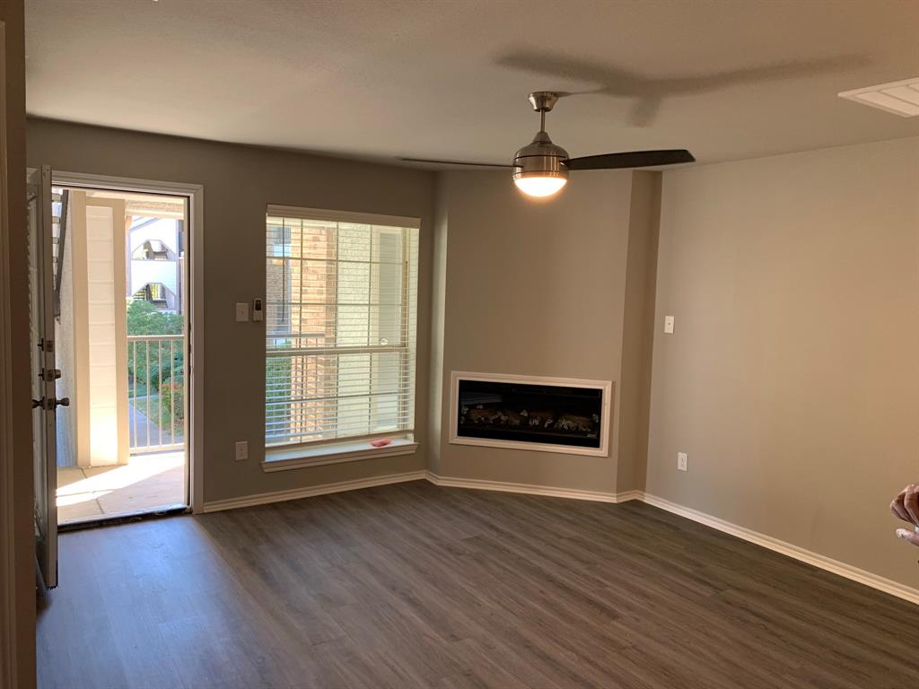 6108 Abrams Road, Unit 514 Dallas, TX 75231 - Photo 4 of 9 a view of an empty room with wooden floor fireplace and a window